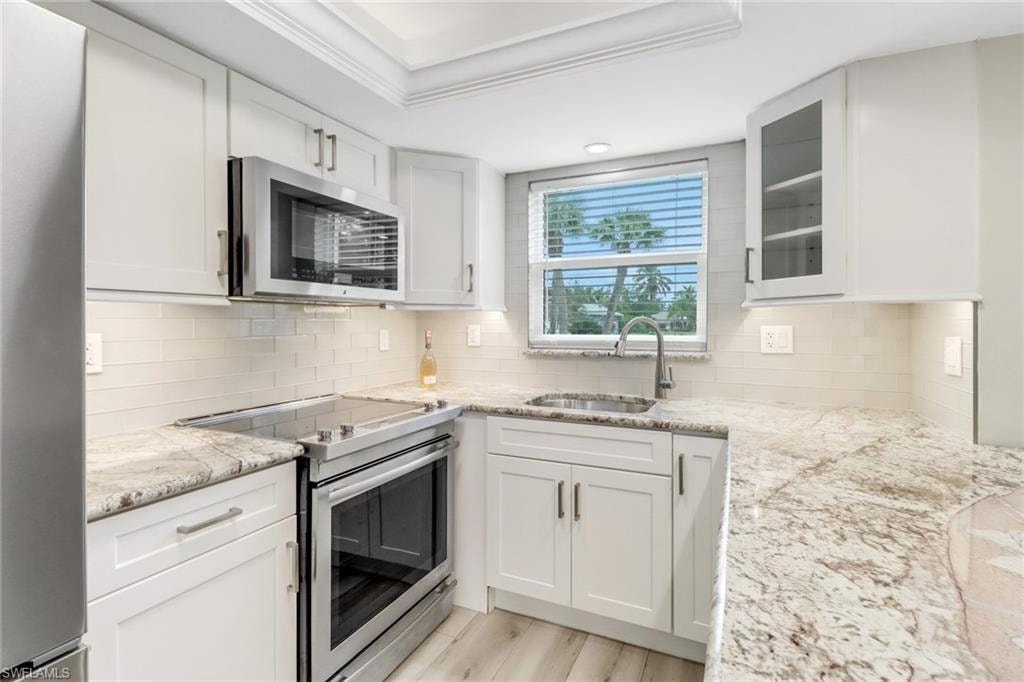 Bright kitchen featuring appliances with stainless steel finishes, and white cabinets and an elegant granite countertop