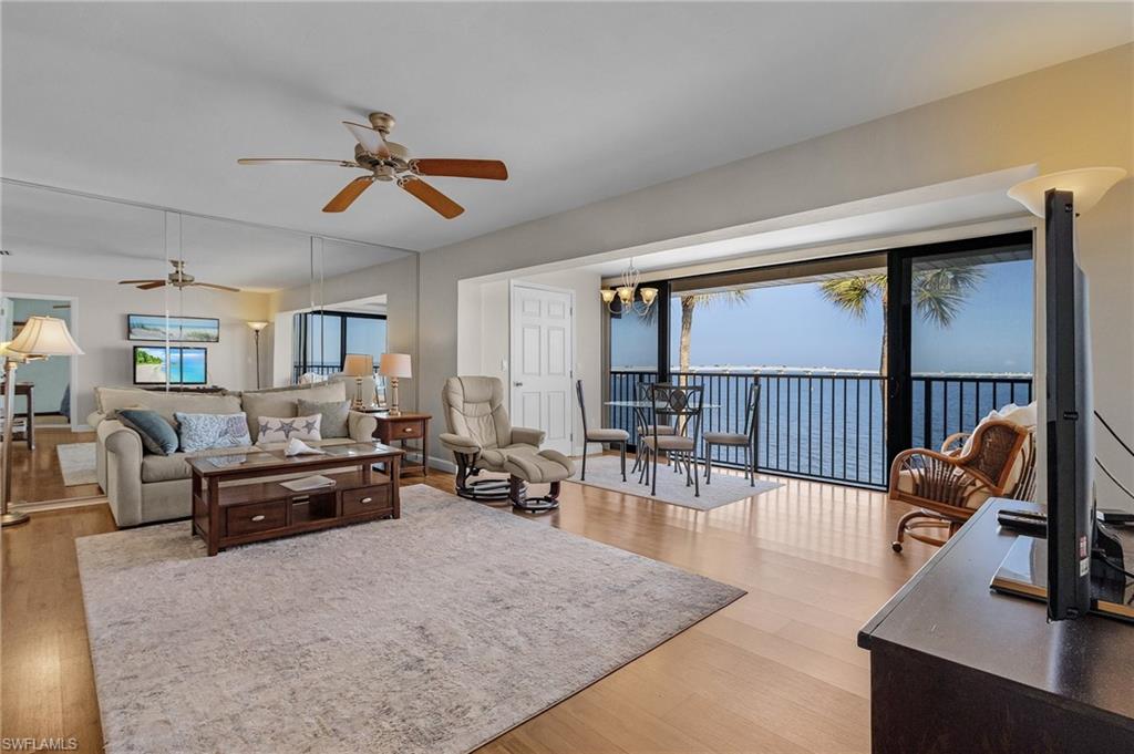 Living room featuring ceiling fan with notable chandelier and wood-type flooring