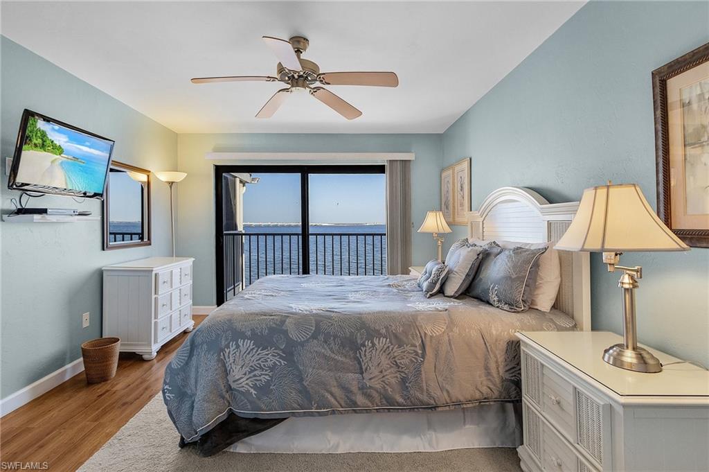 Bedroom with ceiling fan, access to outside, light wood-type flooring, and a water view