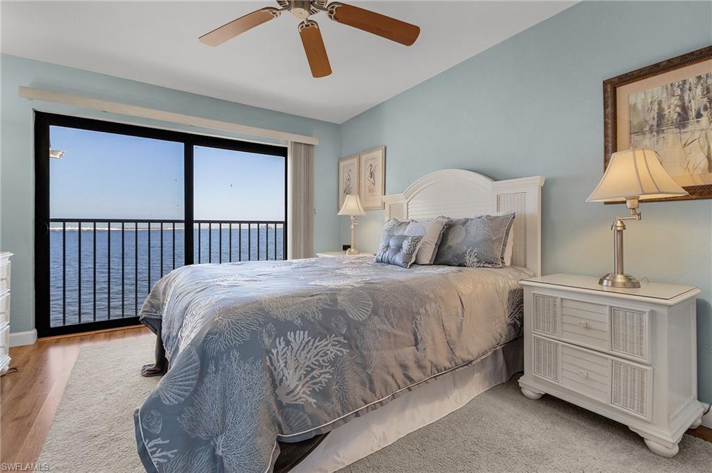 Bedroom featuring ceiling fan, access to exterior, light hardwood / wood-style floors, and a water view