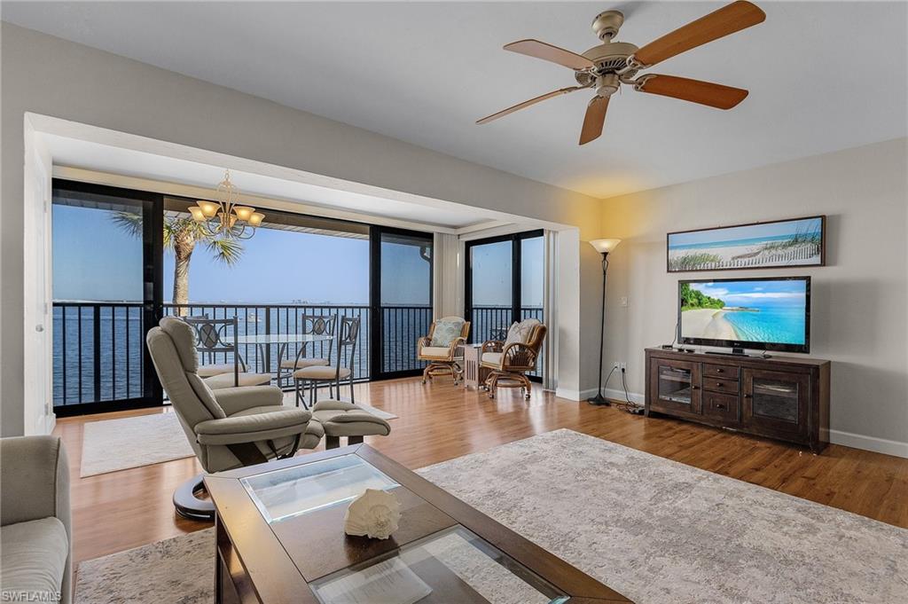 Living room with hardwood / wood-style floors and ceiling fan with notable chandelier