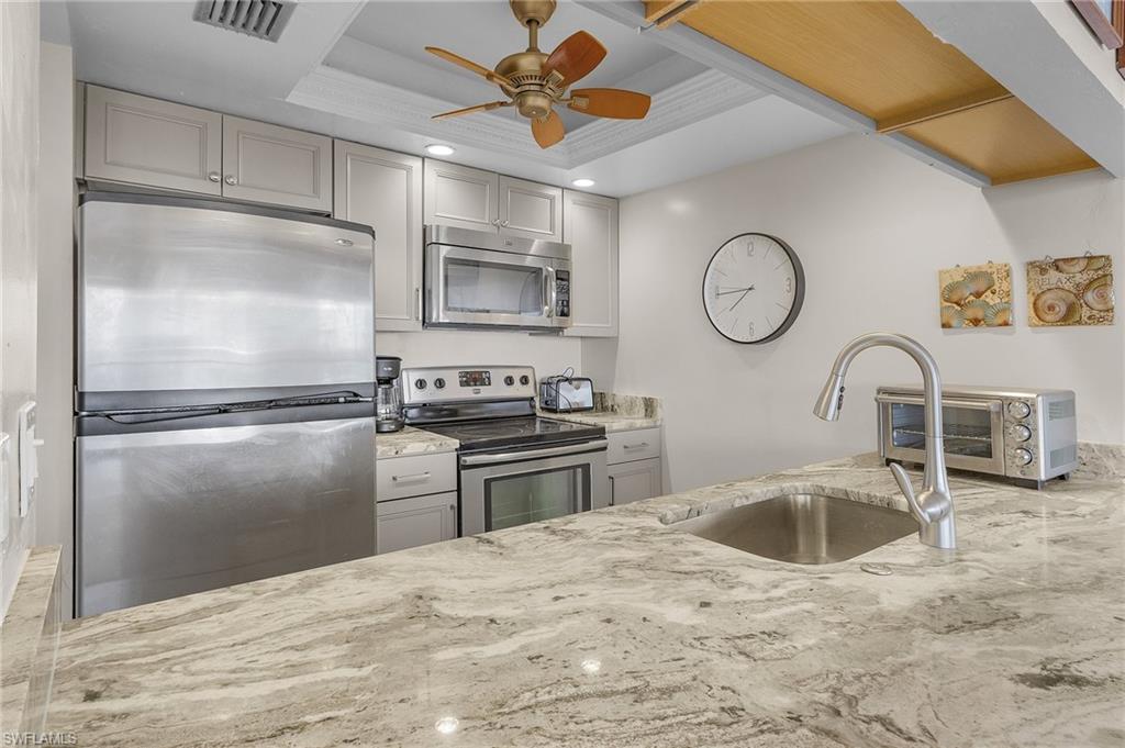 Kitchen featuring stainless steel appliances, sink, a raised ceiling, ceiling fan, and gray cabinets