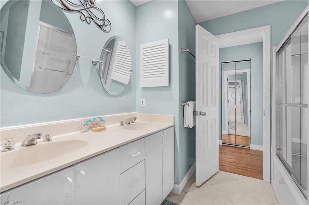 Bathroom featuring enclosed tub / shower combo, tile patterned flooring, and vanity