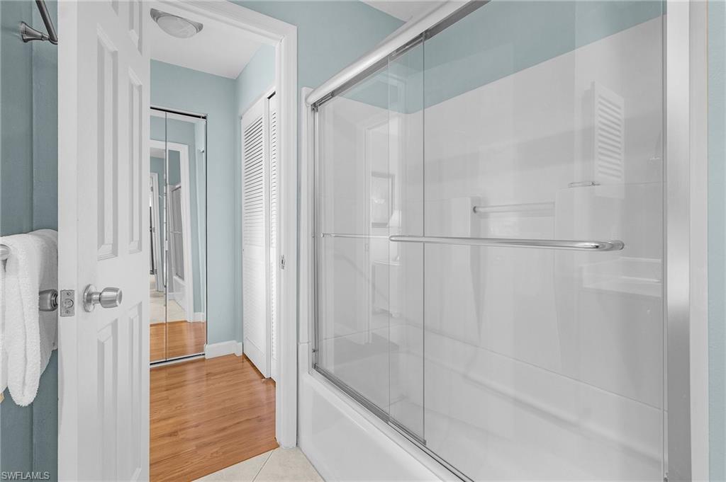 Bathroom with tile patterned flooring and shower / bath combination with glass door
