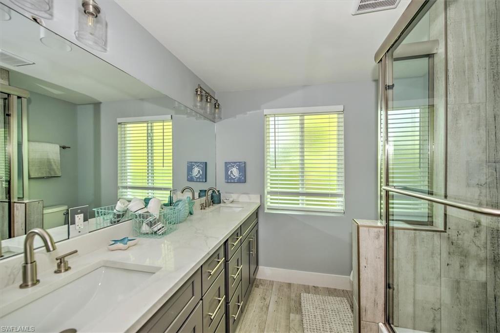 Bathroom featuring toilet, a shower with shower door, wood-type flooring, and vanity