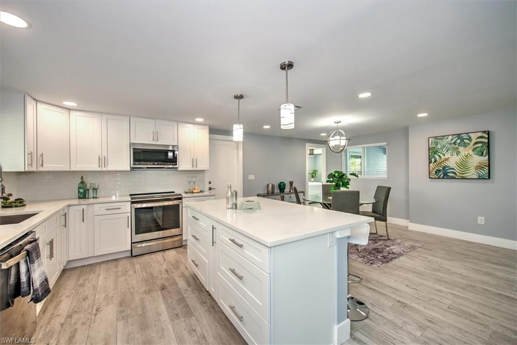 Kitchen with stainless steel appliances, sink, white cabinetry, a center island, and pendant lighting