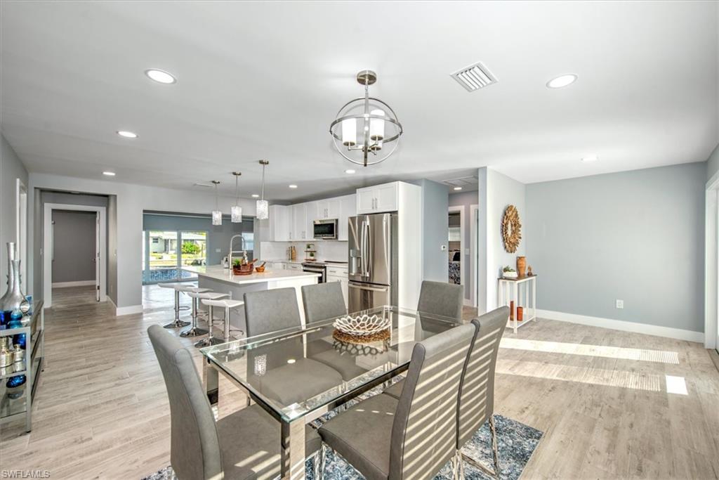 Dining space featuring sink, light wood-type flooring, and a notable chandelier