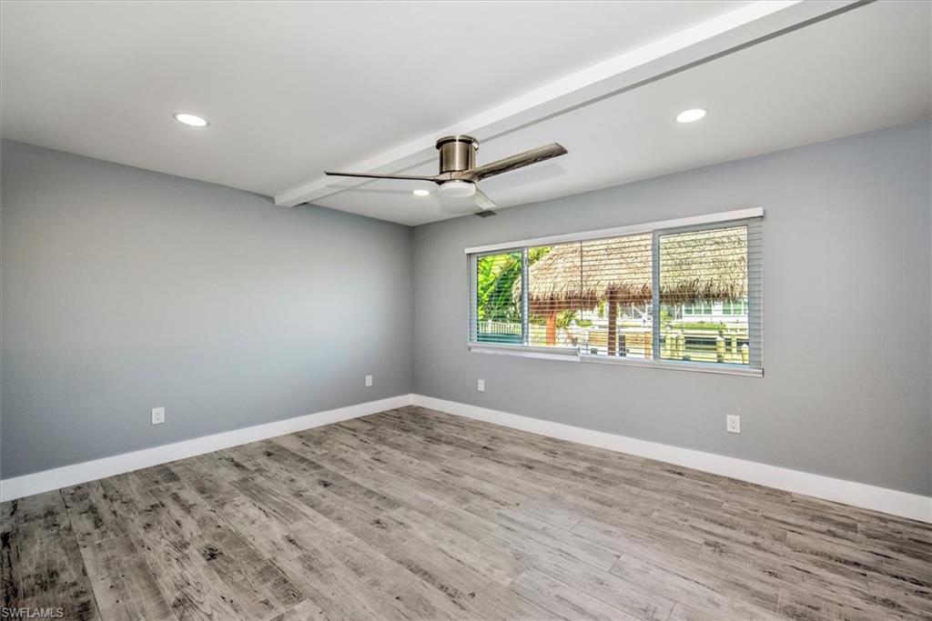 Unfurnished room with light wood-type flooring, beam ceiling, and ceiling fan