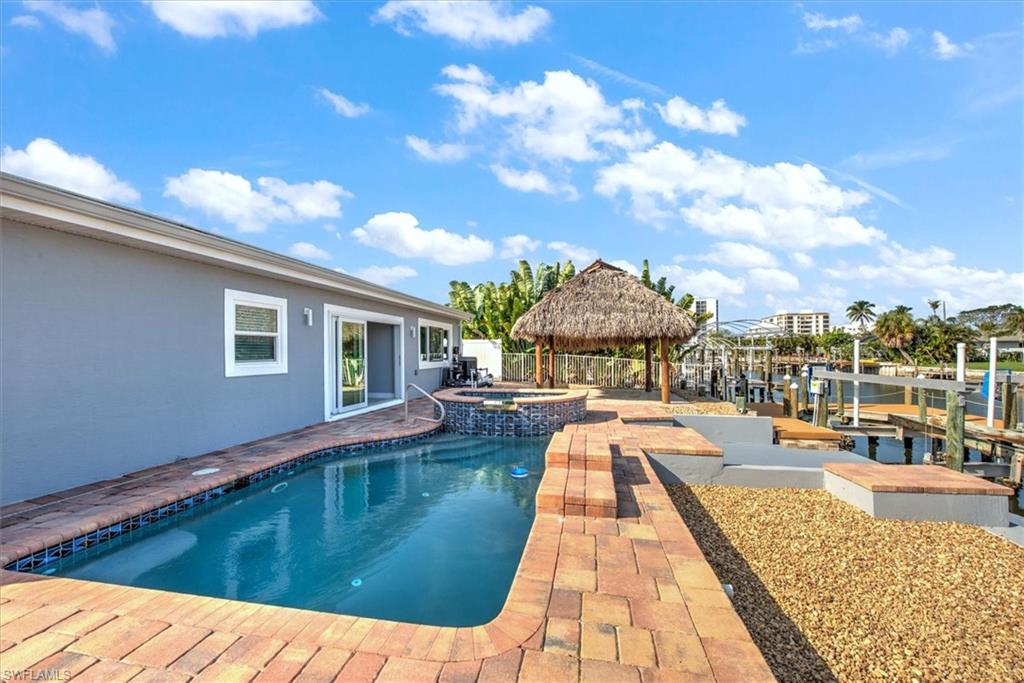 View of pool with a patio, a gazebo, an in ground hot tub, and a water view