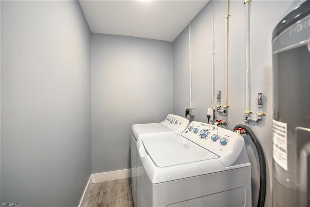 Laundry area featuring washer and dryer, strapped water heater, and hardwood / wood-style floors