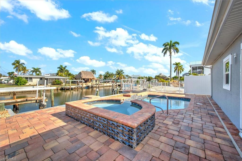 View of swimming pool featuring a dock, a patio area, an in ground hot tub, and a water view