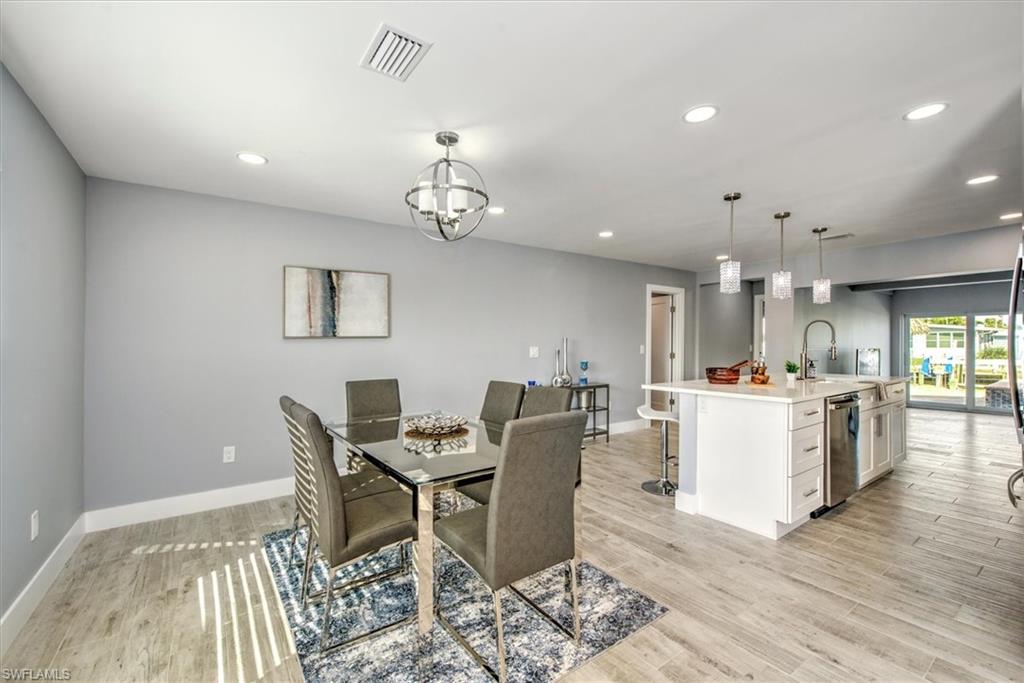 Dining space with sink, light wood-type flooring, and an inviting chandelier
