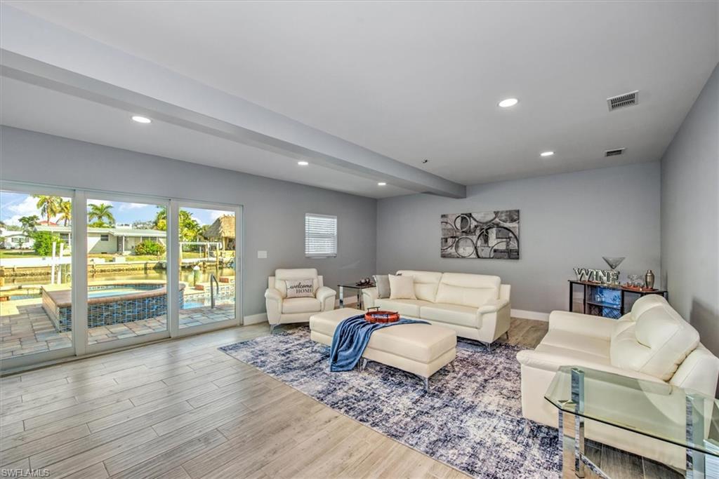 Living room with light wood-type flooring and beamed ceiling
