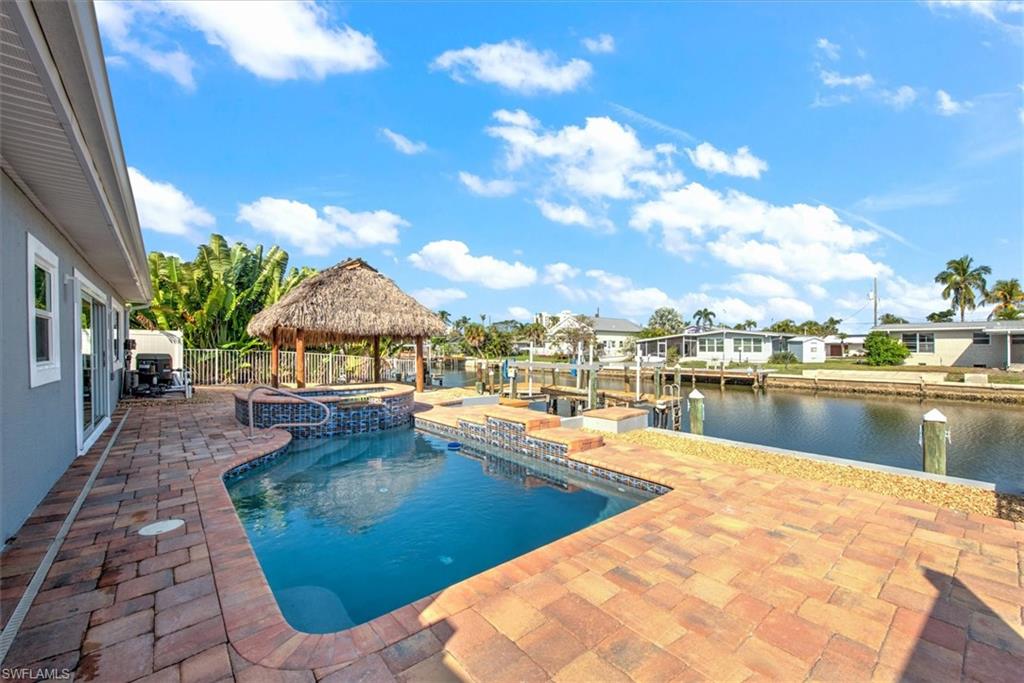 View of swimming pool featuring a gazebo, a patio area, an in ground hot tub, and a water view