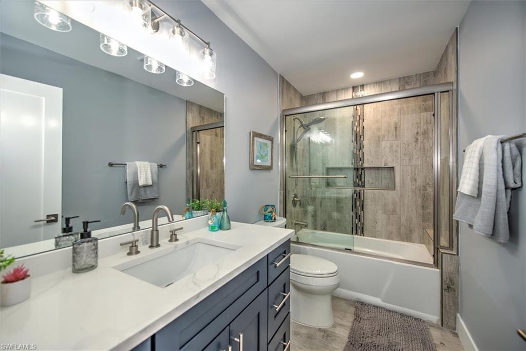Full bathroom featuring bath / shower combo with glass door, vanity, and toilet