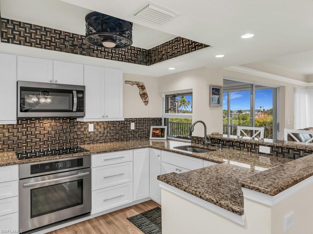 Kitchen with sink, white cabinets, a raised ceiling, and stainless steel appliances
