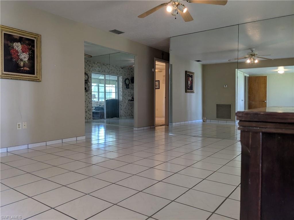 Empty room with a ceiling fan and light tile patterned flooring
