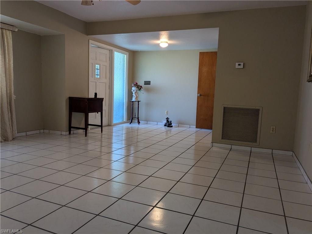 Empty room with light tile patterned floors and a ceiling fan
