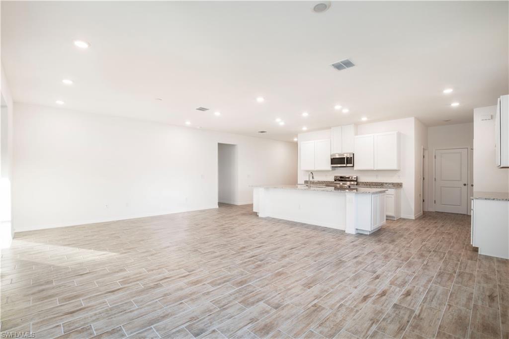 Kitchen with white cabinets, wood tiled floors, open floor plan, and recessed lighting