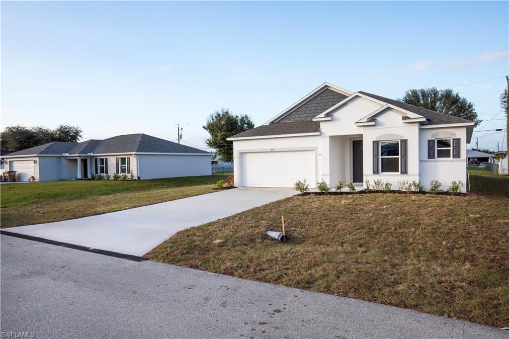 Single story home featuring driveway, a front yard, stucco siding, an attached garage, and a shingled roof