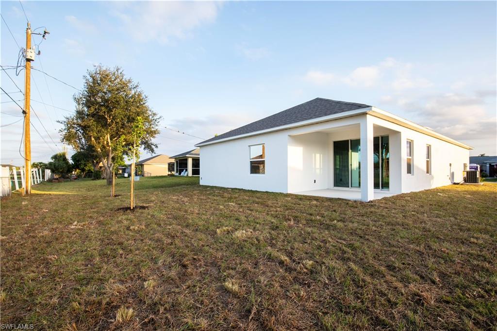 Back of property featuring stucco siding, a patio, a lawn, and roof with shingles
