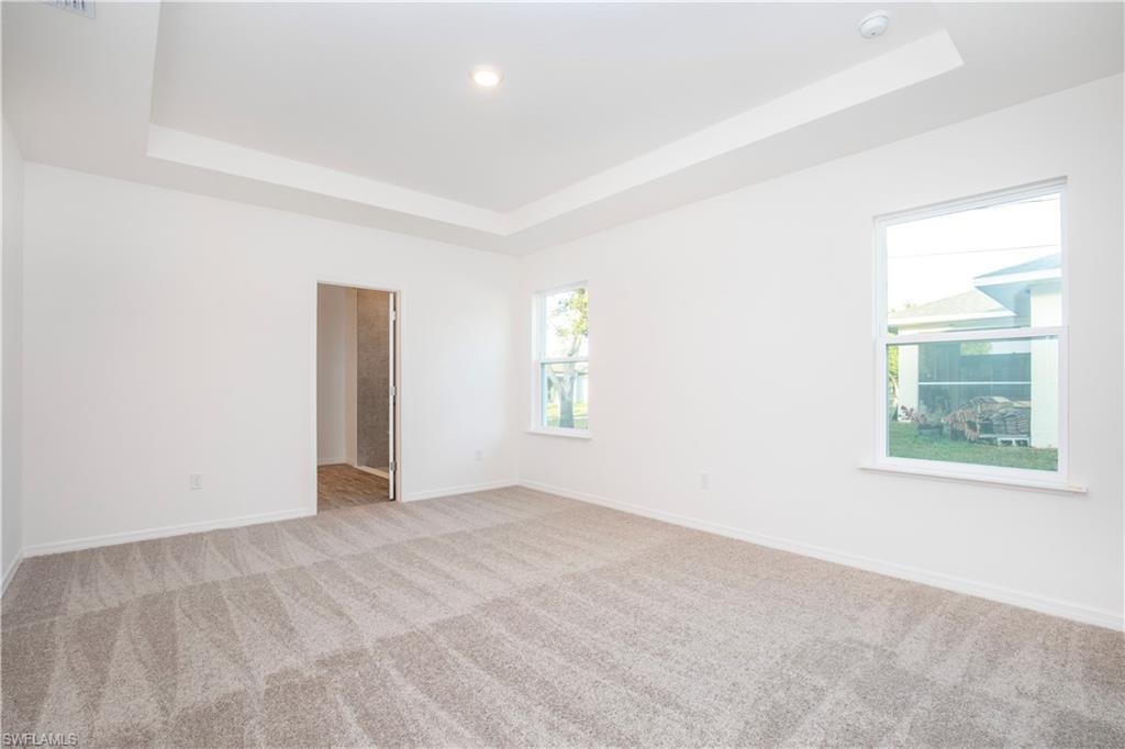 Carpeted spare room featuring a raised ceiling