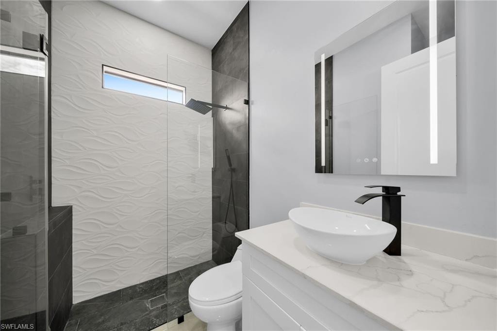 Bathroom with toilet, vanity, and a tile shower