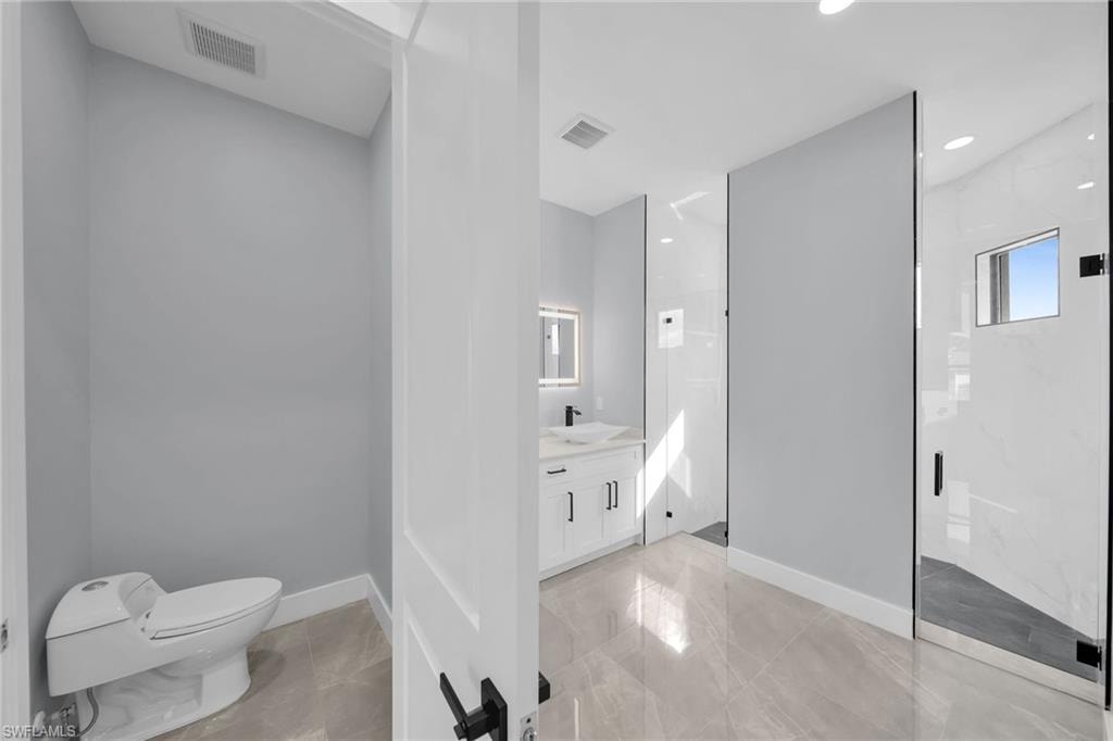 Bathroom featuring toilet, vanity, and tiled shower