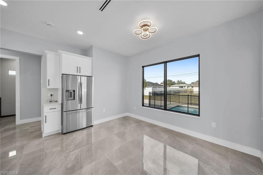 Kitchen featuring white cabinets and stainless steel fridge