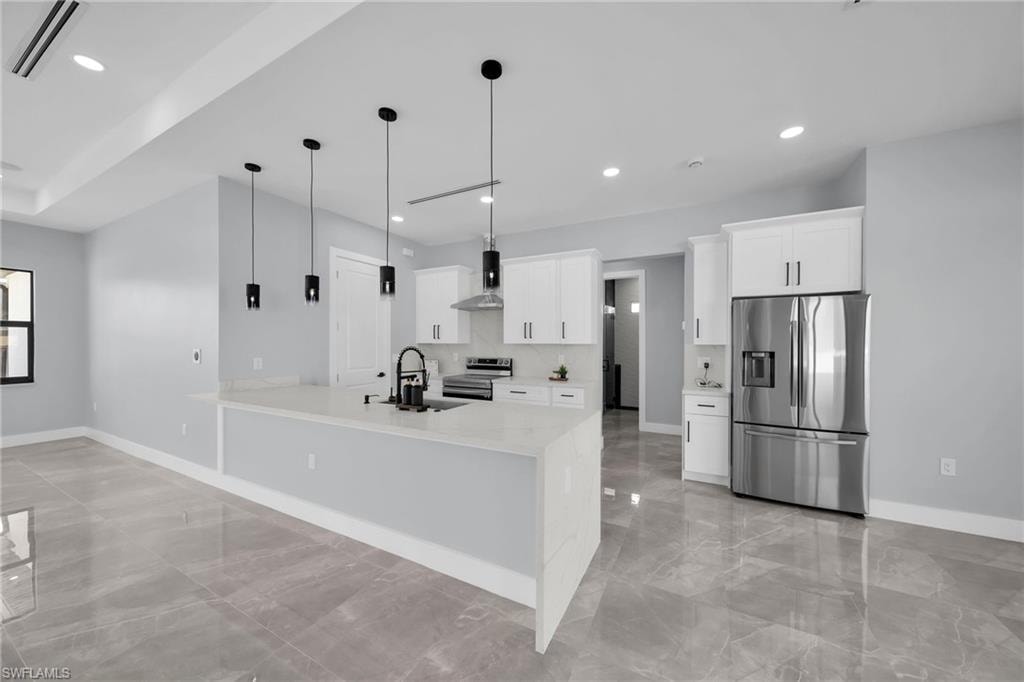 Kitchen with appliances with stainless steel finishes, sink, white cabinetry, and decorative light fixtures