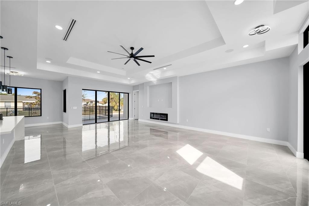 Unfurnished living room with ceiling fan and a tray ceiling