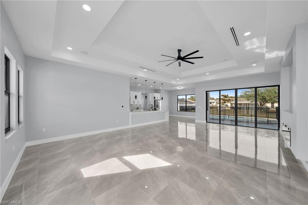 Unfurnished living room featuring ceiling fan and a tray ceiling