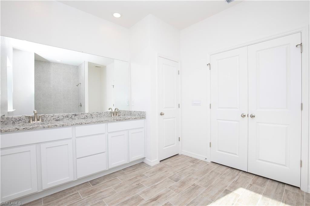 Full bathroom with tiled shower, double vanity, wood tiled floors, and recessed lighting