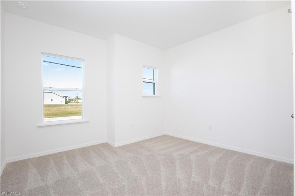 Unfurnished room with baseboards and light colored carpet