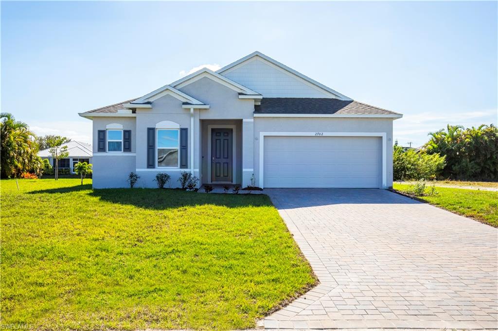 View of front of property featuring stucco siding, decorative driveway, and a front lawn