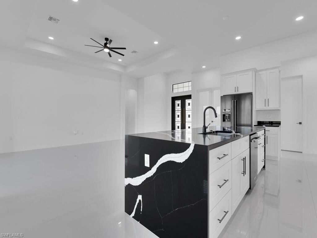 Kitchen featuring stainless steel dishwasher, high quality fridge, a tray ceiling, and white cabinetry