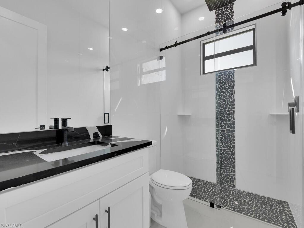 Bathroom featuring a shower with shower door, vanity, and toilet