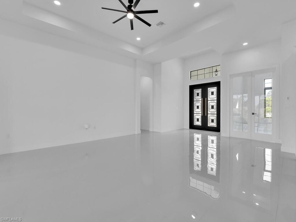 Tiled entryway featuring ceiling fan, french doors, and a tray ceiling