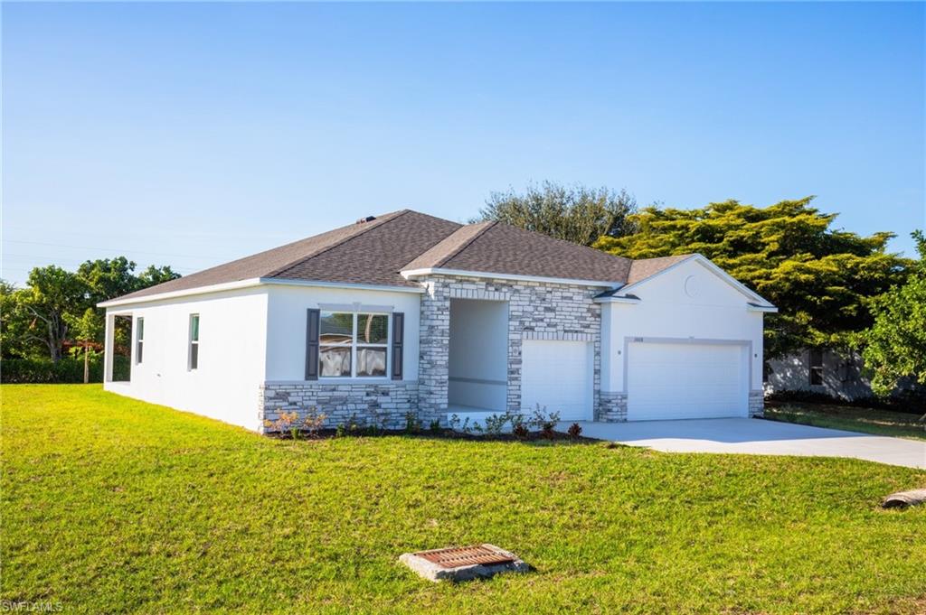 Ranch-style house with a front lawn, stone siding, stucco siding, an attached garage, and driveway