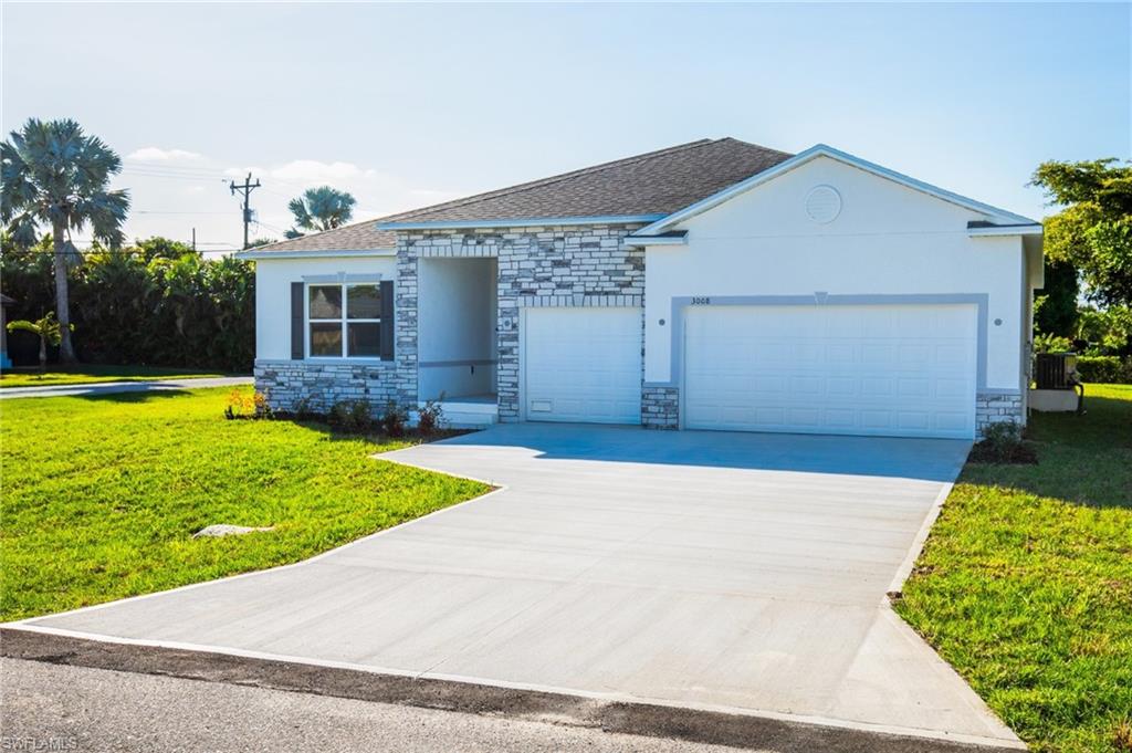 Ranch-style house featuring a front yard, stone siding, concrete driveway, and a shingled roof