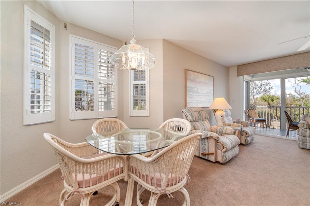 Carpeted dining area with ceiling fan with notable chandelier