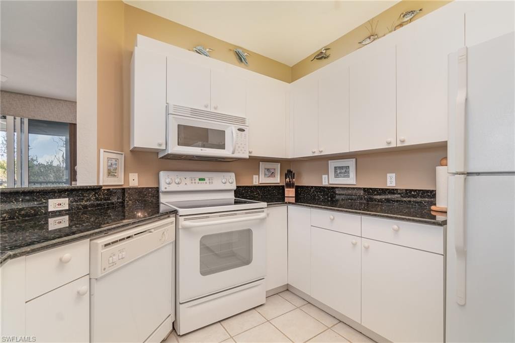 Kitchen featuring light tile patterned flooring, white cabinets, and white appliances