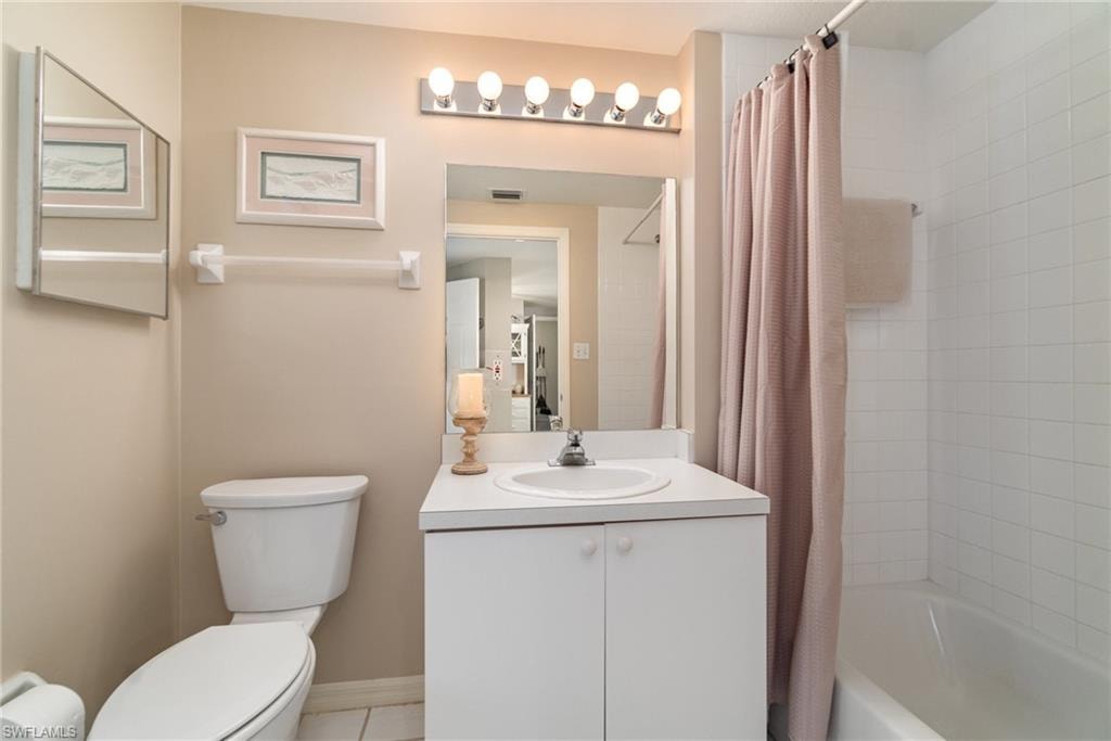 Full bathroom with tile patterned floors, vanity, toilet, and shower / bath combo with shower curtain