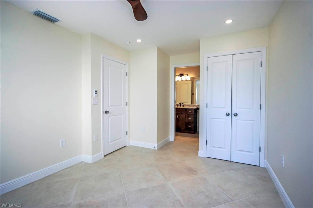 Unfurnished bedroom with ceiling fan, light tile patterned floors, a closet, and ensuite bath