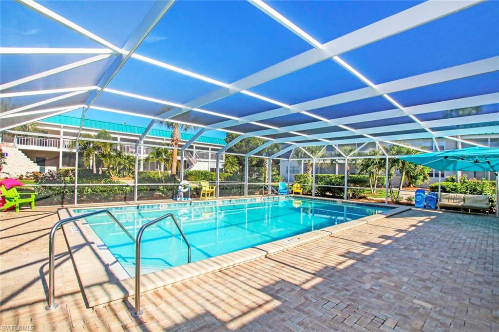 View of pool with glass enclosure and a patio