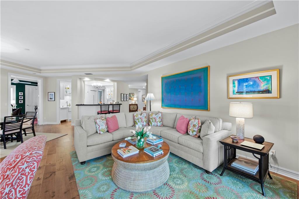 Living room featuring crown molding, hardwood / wood-style floors, and a raised ceiling