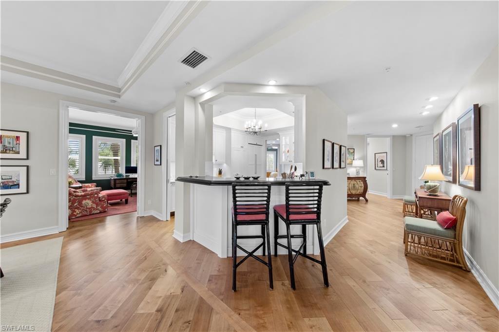 Kitchen with light wood-type flooring, a chandelier, crown molding, and a tray ceiling