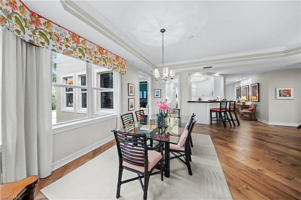 Dining room with ornamental molding, a raised ceiling, and hardwood / wood-style floors