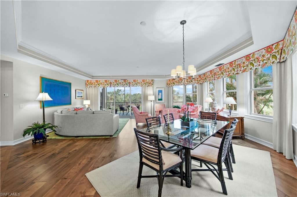 Dining area with wood-type flooring, crown molding, an inviting chandelier, and a tray ceiling