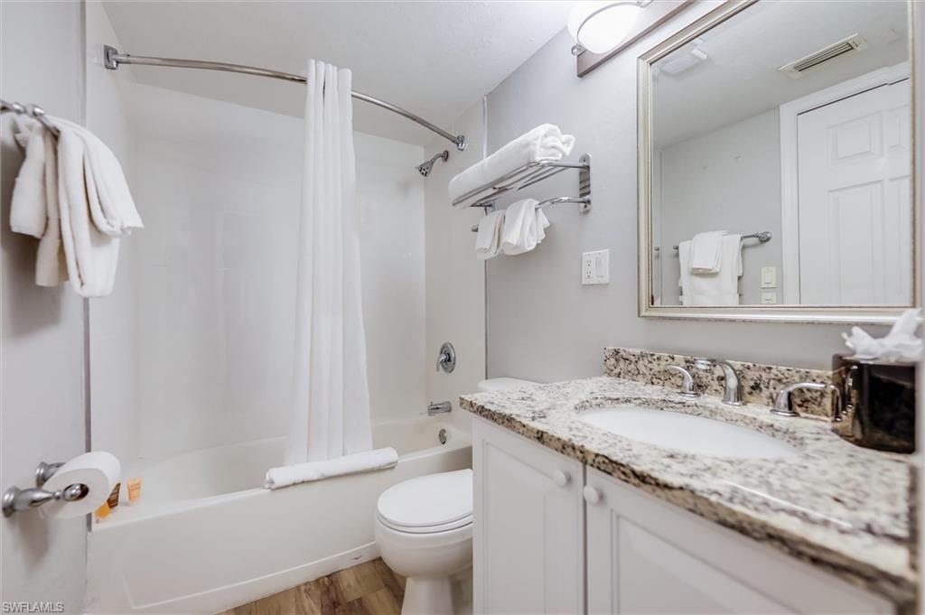 Full bathroom with shower / tub combo with curtain, wood-type flooring, toilet, and vanity